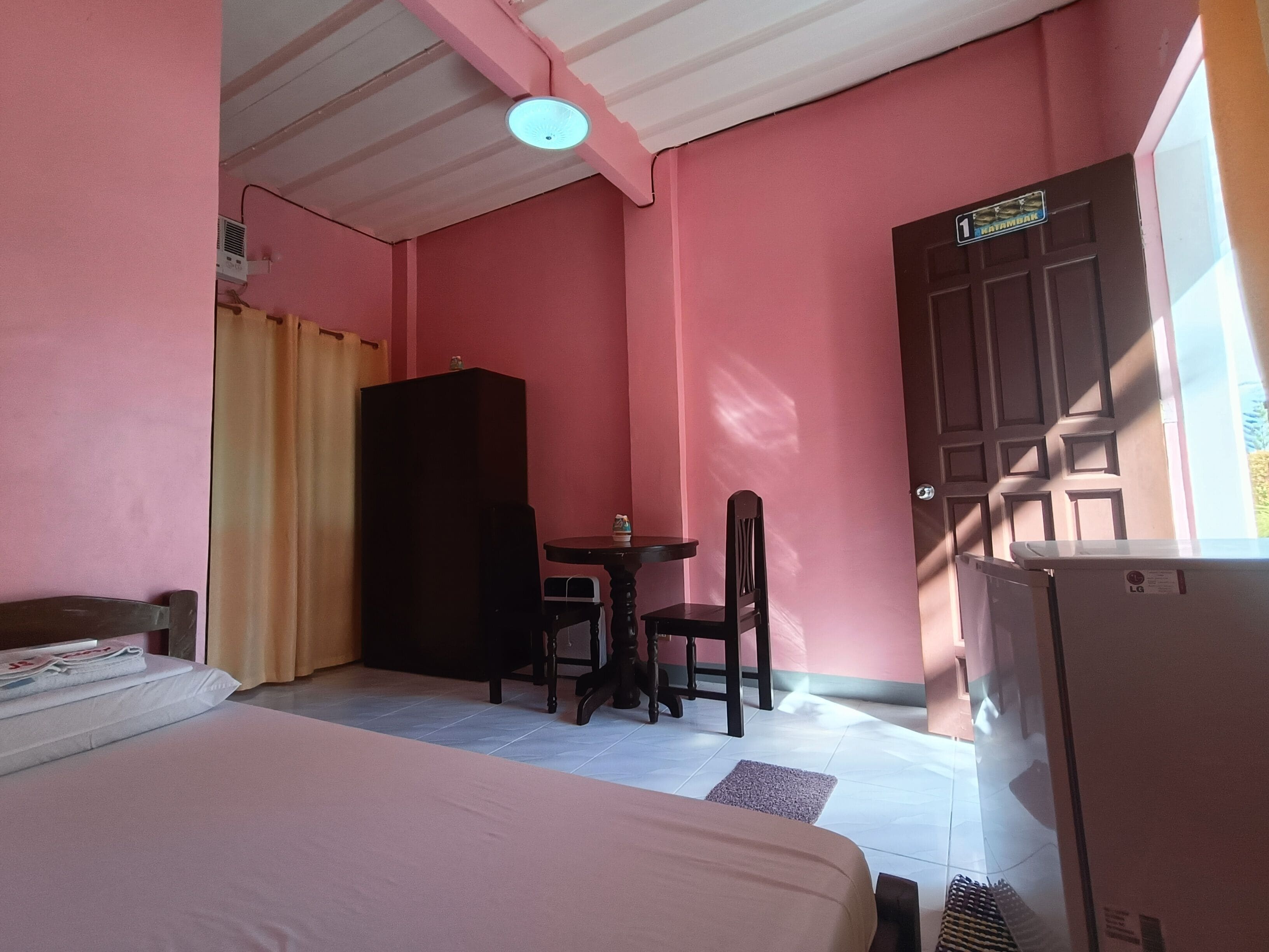 A room with a bed, a desk with a chair, a wardrobe, and a door.