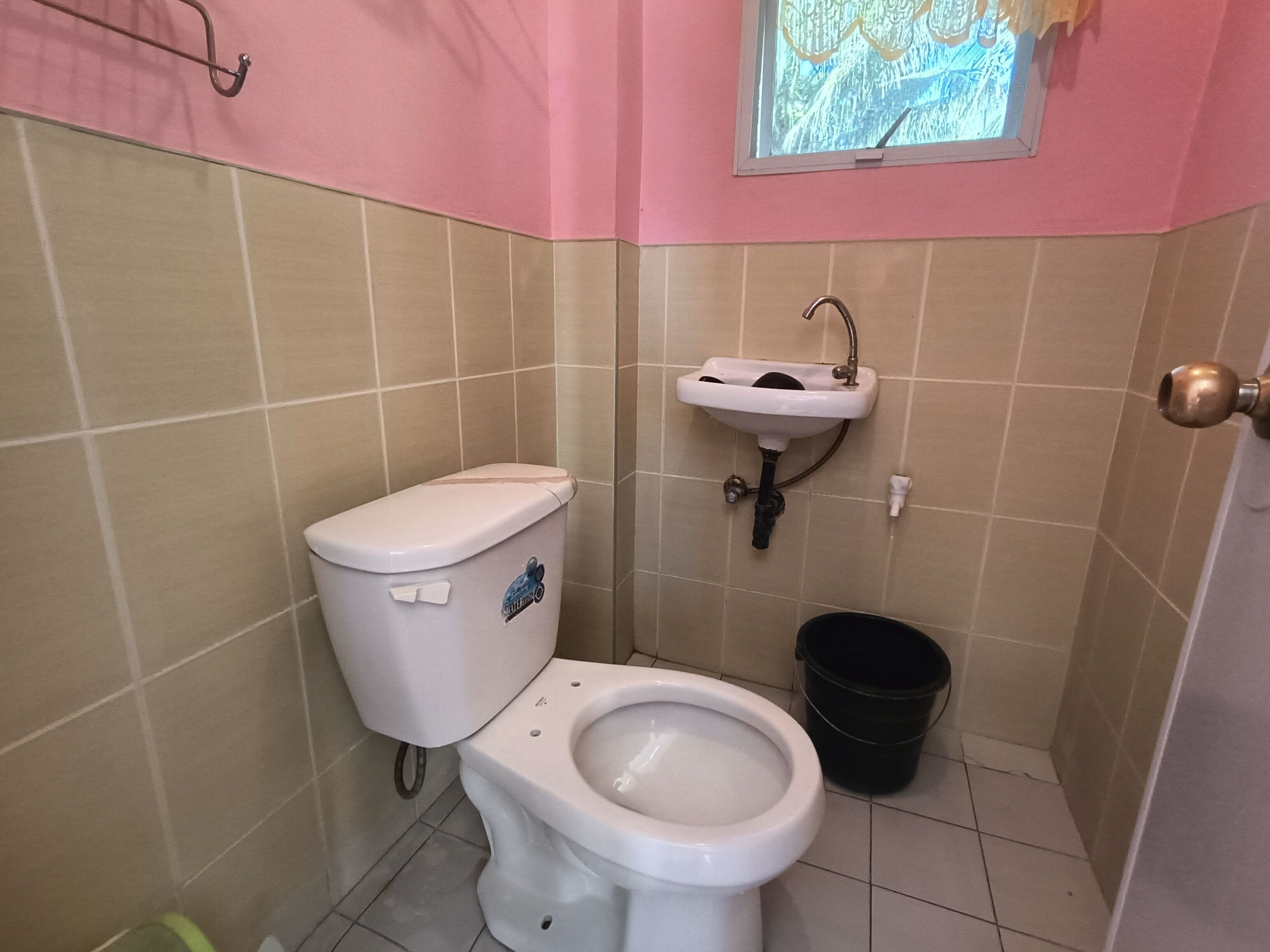 A small bathroom with a toilet, sink, and a window.