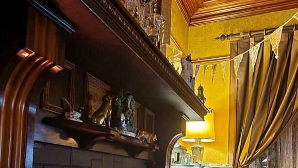 Une pièce chaleureuse avec une cheminée, des meubles en bois et un canapé bleu à motifs.