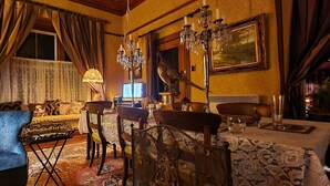 Un coin repas avec une table dressée pour quatre personnes, un fauteuil bleu et un lustre.