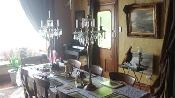 Comedor con techo de madera, candelabro, mesa lista para cuatro personas y alfombra con diseño.