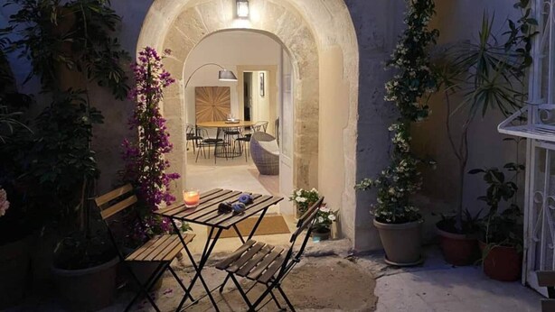 An outdoor patio area with a stone archway, a wooden table with chairs, and potted plants. - Croce Luxury Apartment with Air Conditioning, Wi-Fi n0975 (Siracusa)