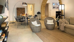 A living room with a dining area, wicker chairs, a sofa, a TV, and a large archway. - Croce Luxury Apartment with Air Conditioning, Wi-Fi n0975 (Siracusa)