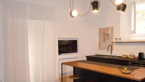 Eine moderne Küche mit einer zentralen Kochinsel, Barhocker, Pendelleuchten und einem Fenster.