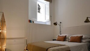 Ein Schlafzimmer mit einem Bett, Deckenventilator, Fenster, Nachttischlampe und Heizkörper.
