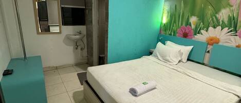 A bedroom with a bed, a bedside table, a mirror, a sink, and a door leading to another room.