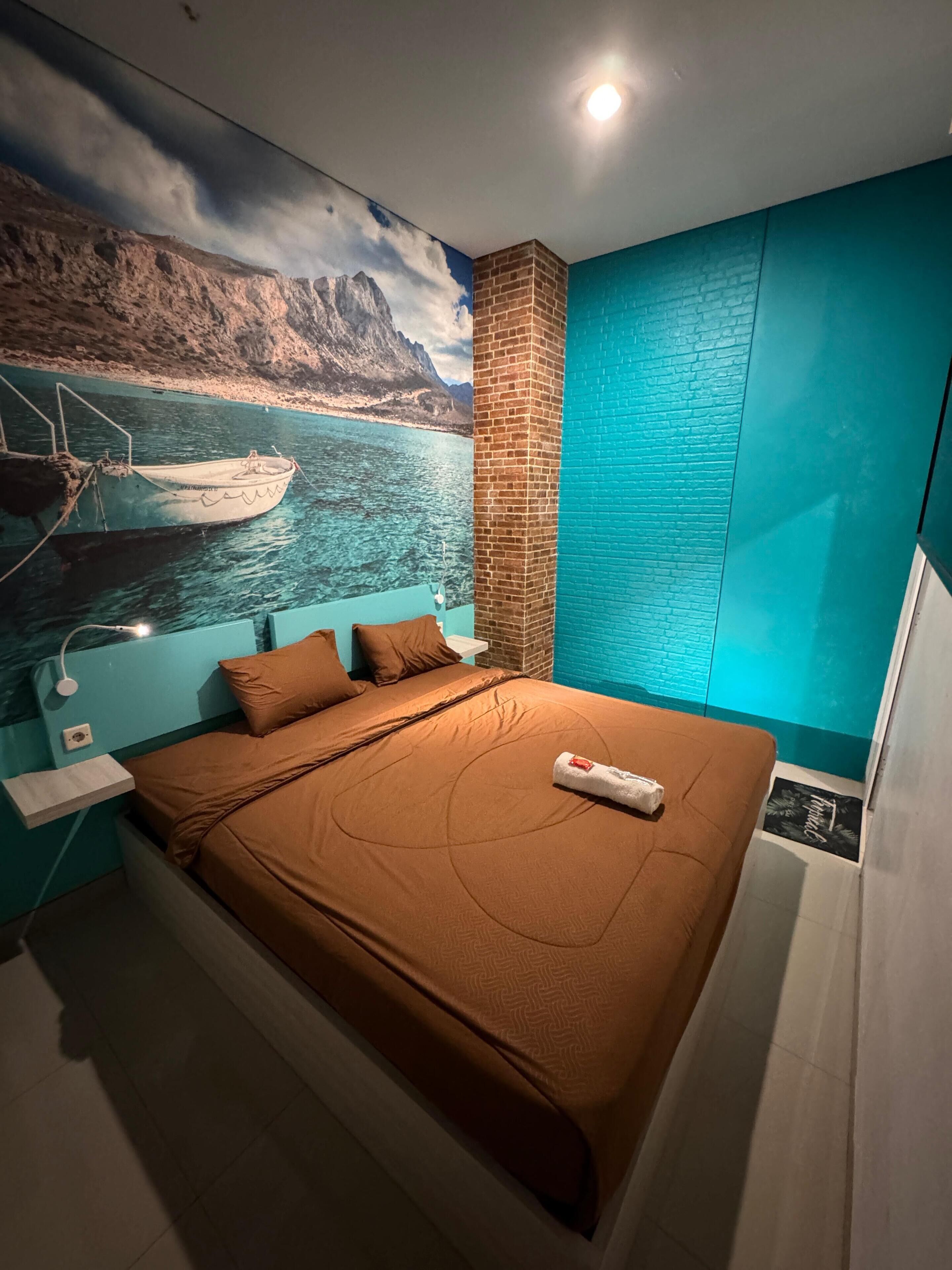 Un dormitorio con cama, mesita de noche, pared de ladrillo decorativa y un mural de un barco en el agua.