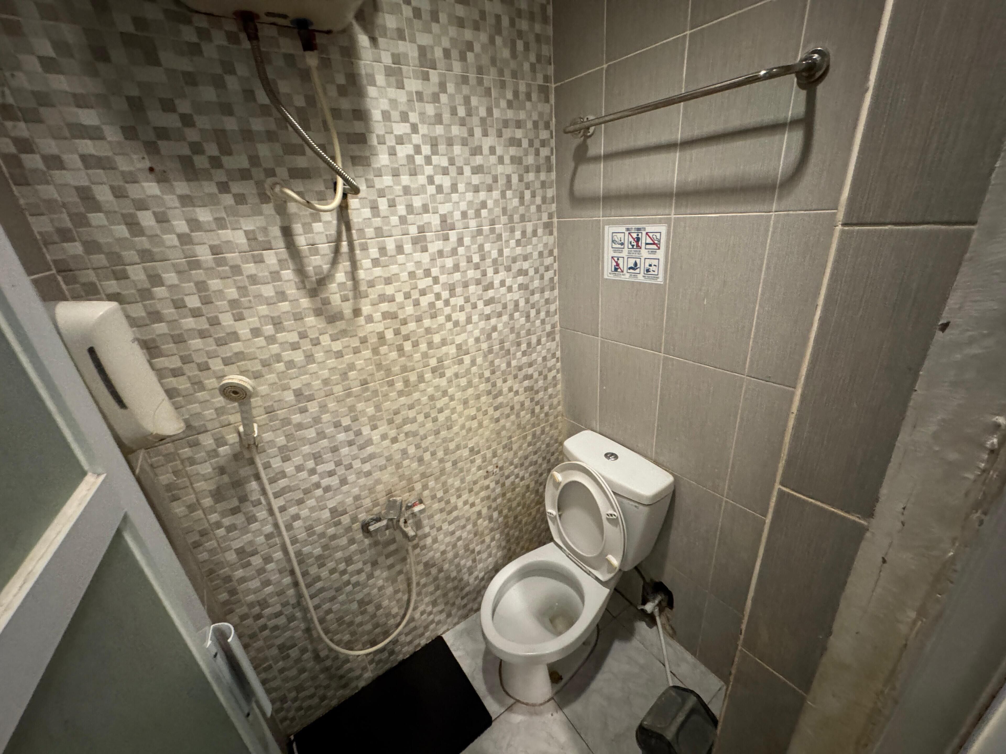 A small bathroom with a toilet, a shower, and a hand dryer.