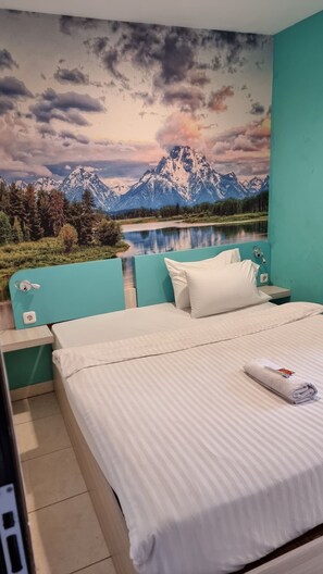 A bedroom with a bed, a nightstand, and a wall mural of a mountain landscape. - COZY CENTRE RESIDENCE SEMARANG (Semarang)