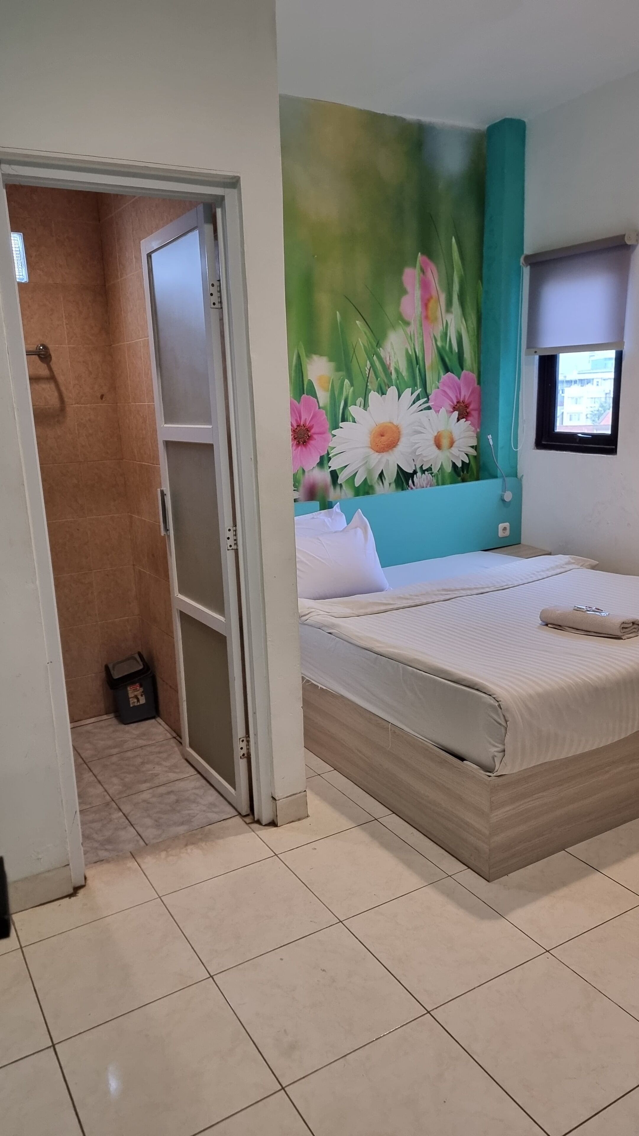 A bedroom with a bed, a window with a view, and a bathroom with a shower.