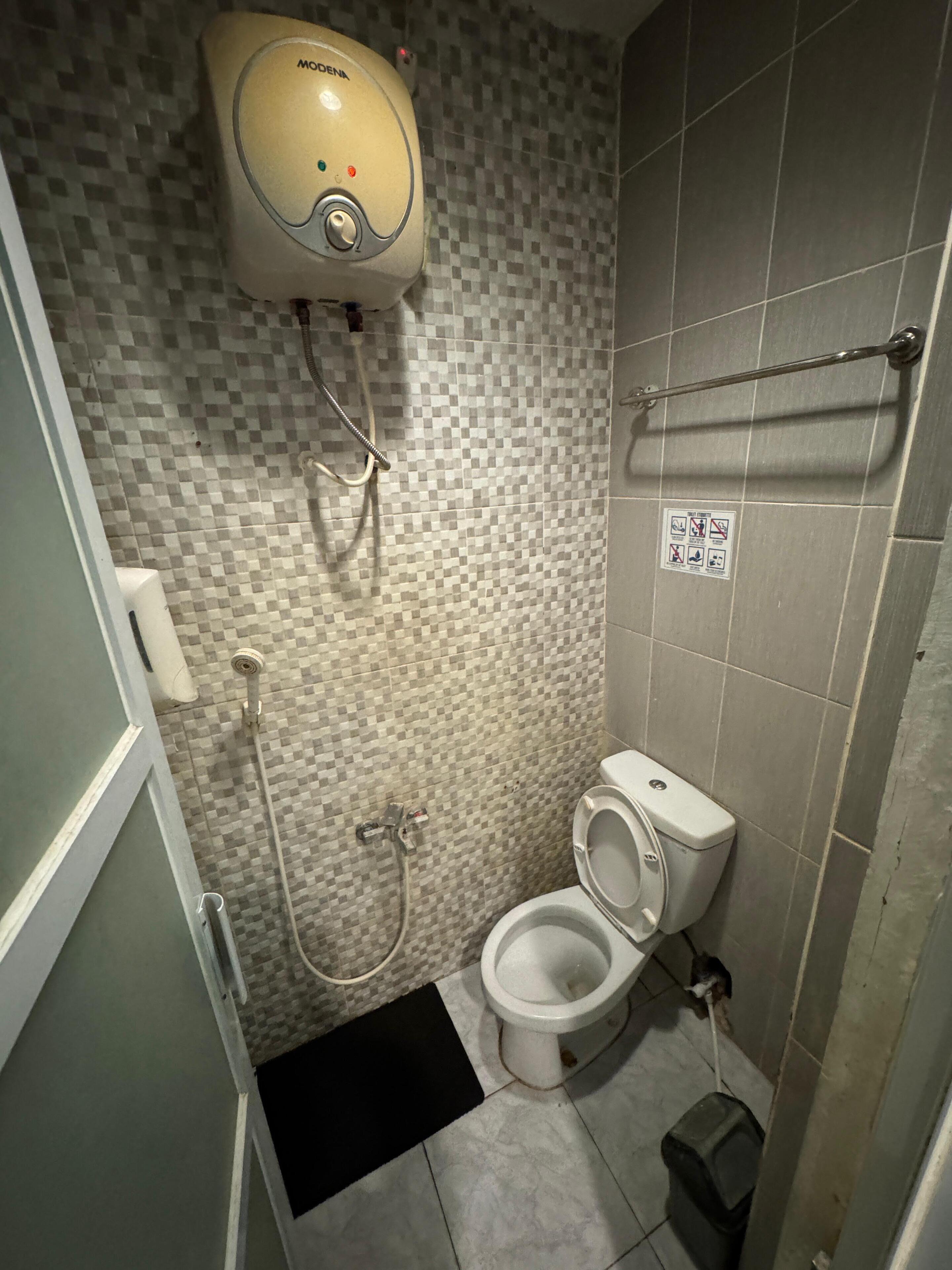 A small bathroom with a toilet, a shower, and a hand dryer.