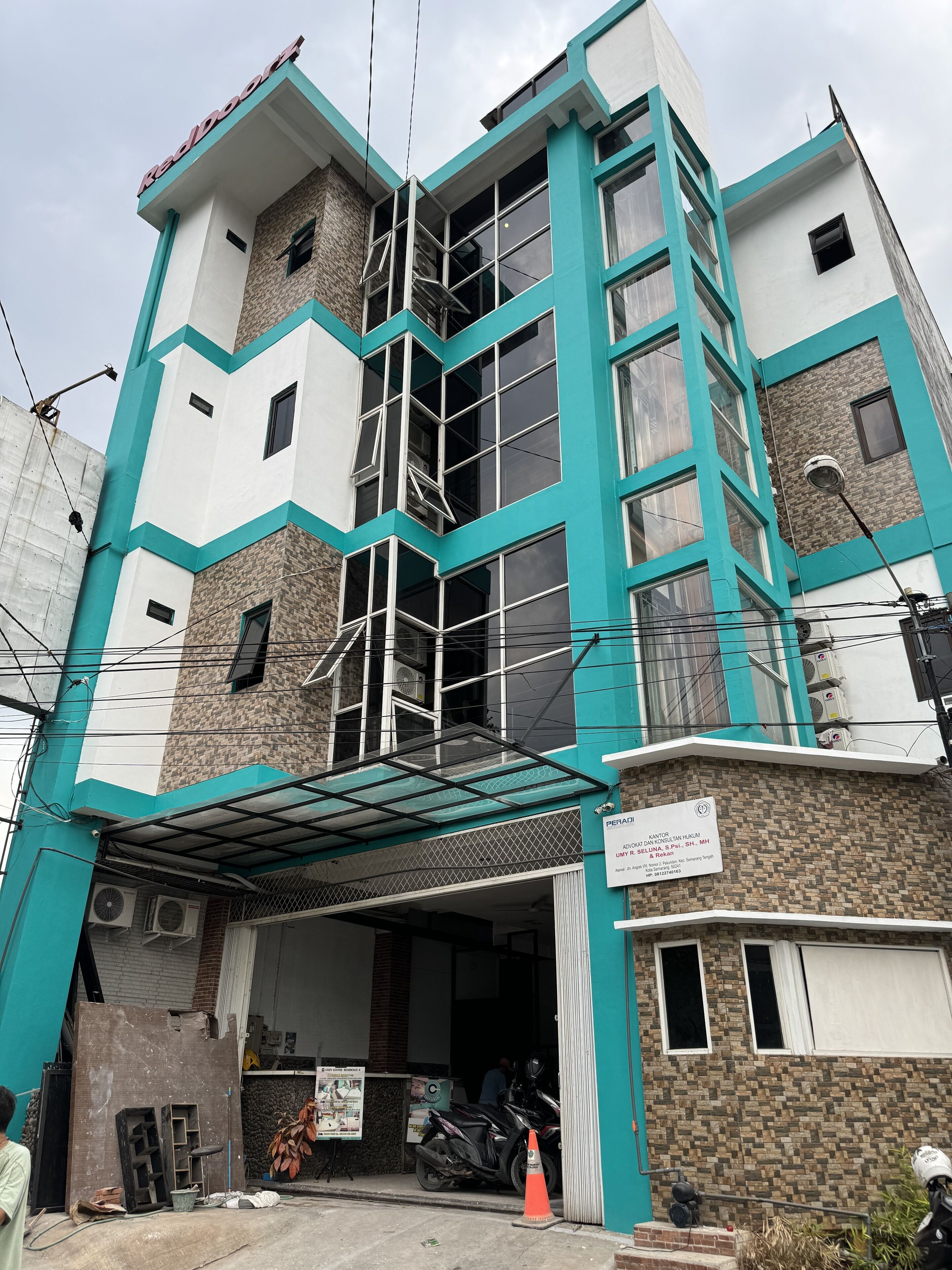 Un edificio a più piani con un design architettonico moderno, caratterizzato da un ingresso ben visibile con una tettoia e una segnaletica che indica uno spazio commerciale o uffici.