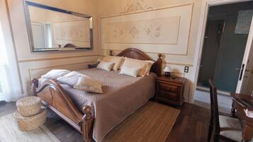 Quarto com cama de madeira, mesa de cabeceira, espelho e porta para um banheiro.