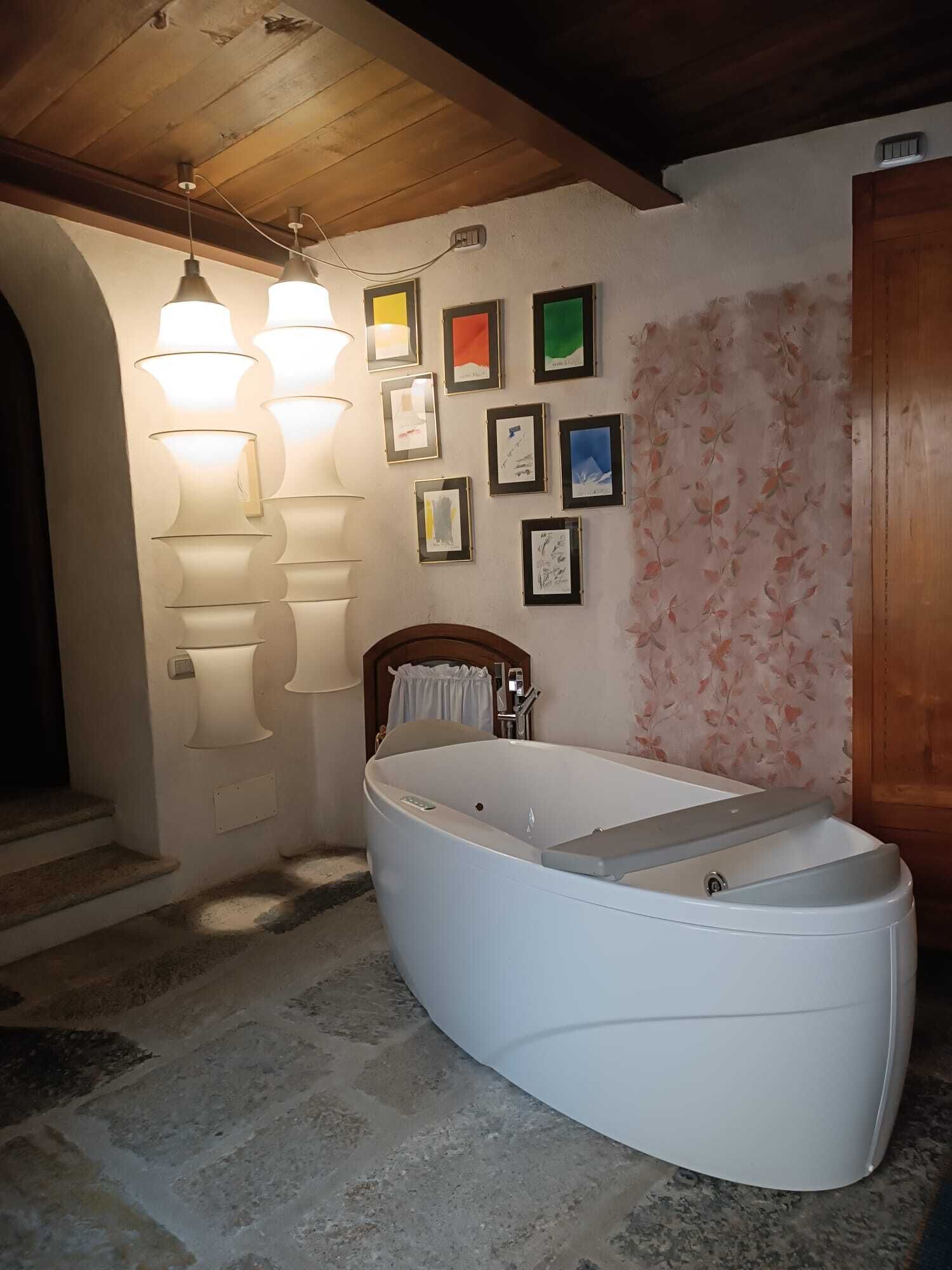 Un baño con una bañera independiente, una puerta de madera y una pared con cuadros.