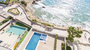 Un complex turístic amb zona de piscina, platja i costa rocosa.