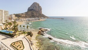 Un complex turístic costaner amb una formació rocosa destacada, una platja i una marina.