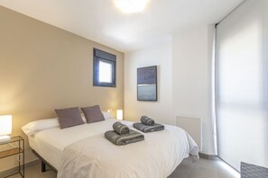 Een moderne hotelkamer met een groot bed, twee nachtkastjes, een raam en een schilderij aan de muur.
