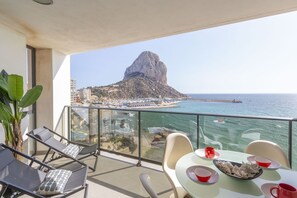 Een balkon met uitzicht op een kustlandschap, inclusief een opvallende rotsformatie en een strand.