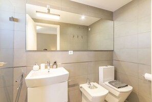Een moderne badkamer met een grote spiegel, een wastafel, een toilet en een douchehoek.