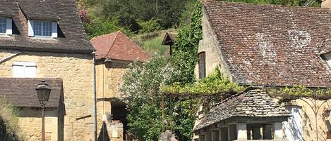 Una calle estrecha en un pueblo histórico con edificios de piedra, una iglesia y un castillo al fondo.