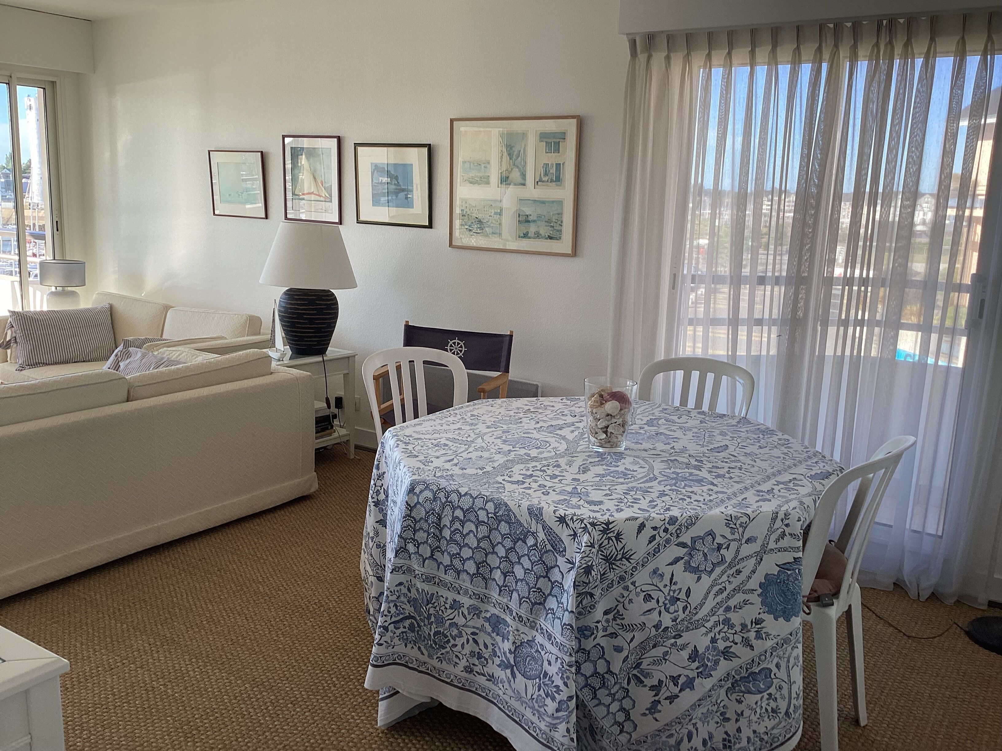 A room with a sofa, a table with a patterned tablecloth, and framed pictures on the wall.