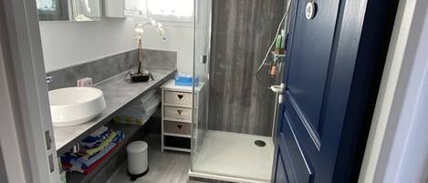 Un baño moderno con ducha, lavabo y tocador.