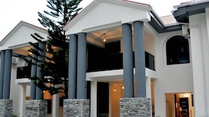 Una casa moderna de dos pisos con fachada simétrica, columnas grandes y un porche cubierto.