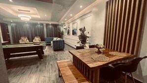 Una sala de estar moderna con una mesa de billar, un sofá azul y una mesa de comedor de madera con sillas negras.