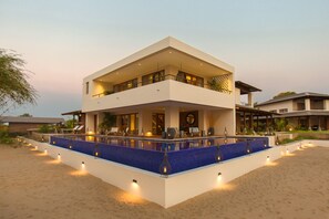 Ein modernes, zweistöckiges Gebäude mit Pool, Sitzgelegenheiten im Freien und einem gut beleuchteten Balkon.
