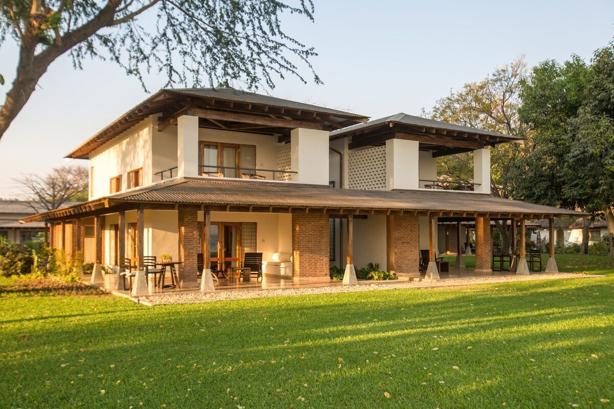 Een huis met twee verdiepingen, een overdekte veranda en een gazon.