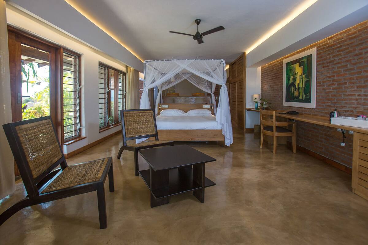 Een slaapkamer met een bed, een bureau, een stoel en een plafondventilator.