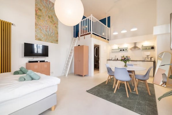 Eine moderne Wohnung mit Schlafzimmer, Essbereich, Küche und einer Treppe zu einer oberen Ebene.