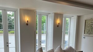 Un salon avec un canapé beige, un pouf assorti et deux appliques murales.