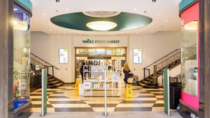 The entrance to Whole Foods Market with a checkered floor, a central display, and a staircase to the right. - Central London - 2 Beds - Sleeps 4 - Lift (London)