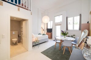 Relax in this serene space with a comfortable bed, dining table, and large mirror.