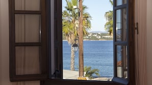 An open window with a view of the sea, palm trees, and a lamp post. - Teresa Spetses (Spetses)