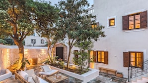 A courtyard with stone flooring, outdoor seating, and a staircase leading to an upper level. - Teresa Spetses (Spetses)