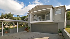 A modern two-story house with a covered patio, a garage, and a landscaped backyard. - A Beachside Getaway 12 by HolidayCo. (KILLCARE)