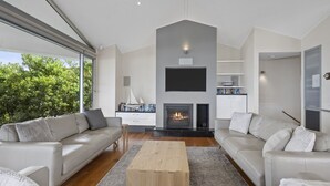 A modern living room with two sofas, a coffee table, a fireplace, and a TV mounted on the wall. - A Beachside Getaway 12 by HolidayCo. (KILLCARE)