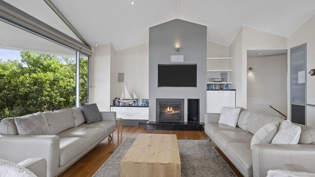 Una sala de estar moderna con dos sofás, una mesa de centro, una chimenea y un televisor montado en la pared.
