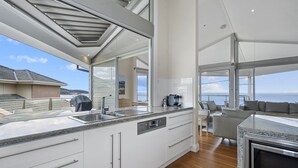 Una cocina moderna con una isla grande, un comedor con vistas al mar y un rincón de descanso acogedor.