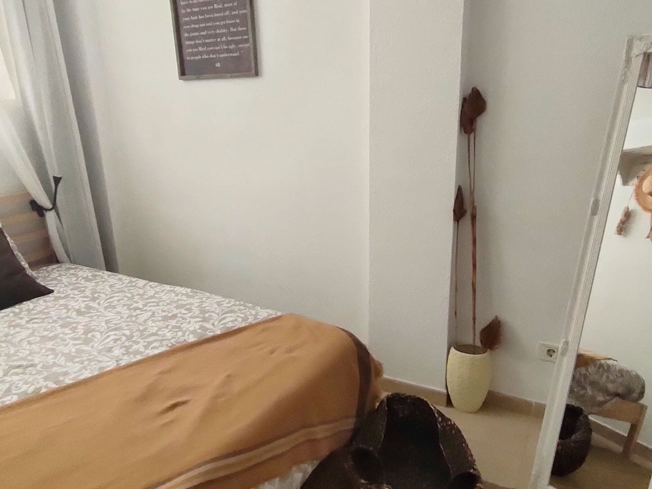 A bedroom with a bed, a mirror, and a wall-mounted sign.