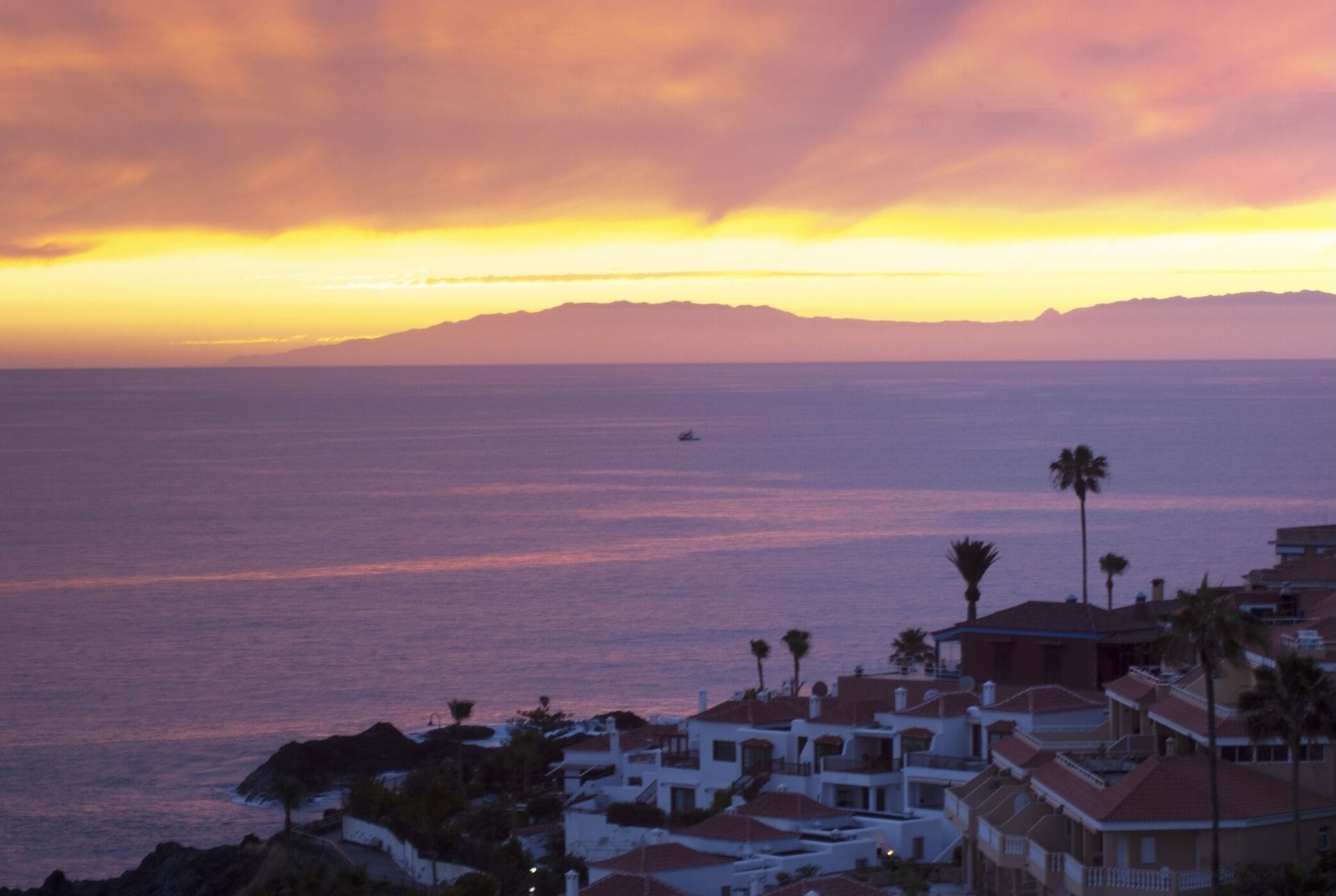 Une ville côtière au coucher du soleil, avec des bâtiments donnant sur la mer.