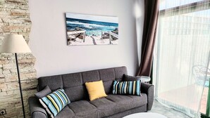 A grey sofa with striped and solid cushions, a white coffee table, and a beach scene painting on the wall. - Tess Dreamlike Mirador with Panoramic Views (Costa Adeje)