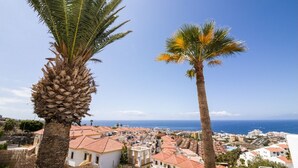 A coastal town with white buildings and red roofs, palm trees, and a clear blue sky. - Tess Dreamlike Mirador with Panoramic Views (Costa Adeje)