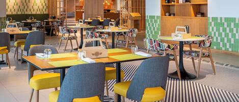 A modern restaurant with multiple tables and chairs, wooden shelves, and a patterned floor.