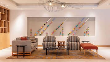 A modern living room with a sofa, armchairs, a coffee table, and a patterned rug.