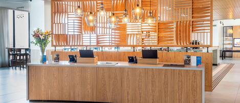 A reception desk with a wooden finish, multiple computer monitors, and a modern chandelier.