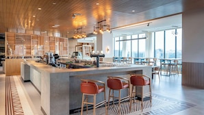 A modern bar area with a central counter, bar stools, and large windows offering a city view. - Hyatt Place Nairobi Westlands (Nairobi)