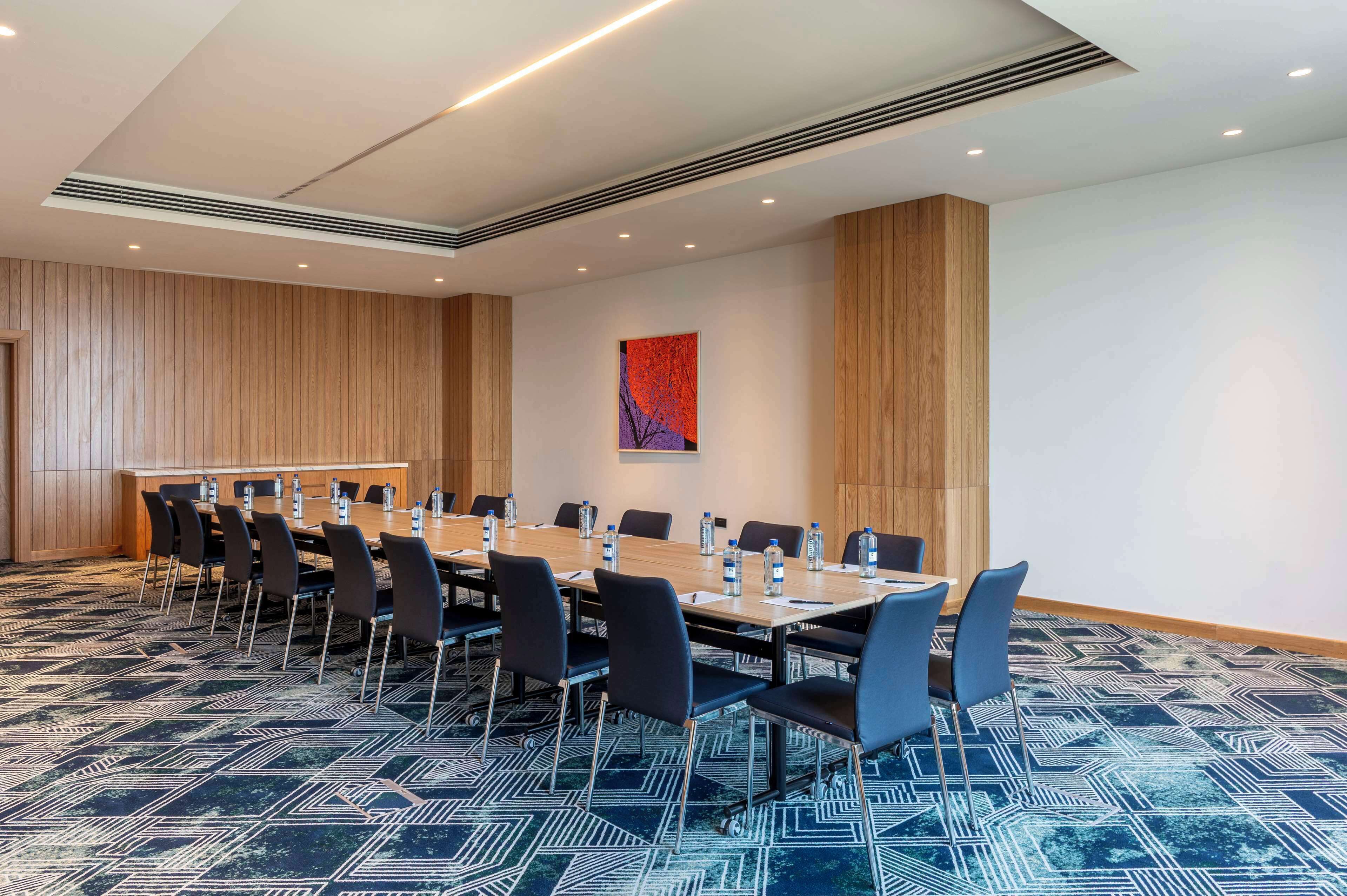 A conference room with a long table, chairs, and a patterned carpet.